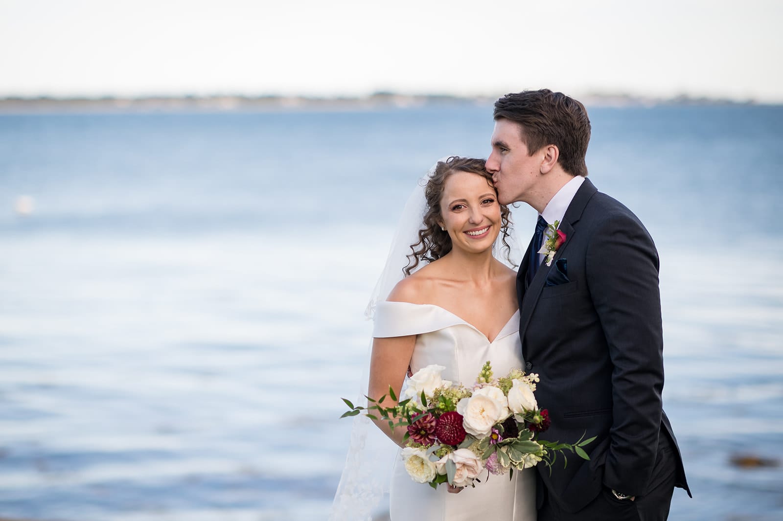 Bride and groom together in front of the ocean at their Stonington, CT wedding captured by Teresa Johnson Photography