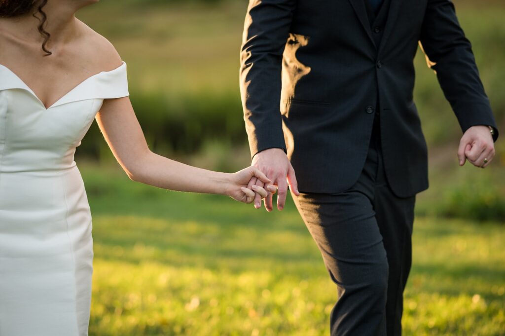bride and groom walk across a sunny field at their stonington ct wedding