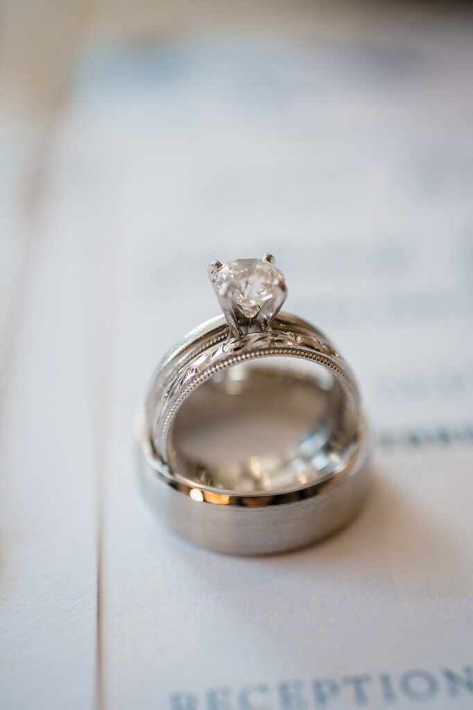 an engagement and wedding rings displayed atop a wedding invitation