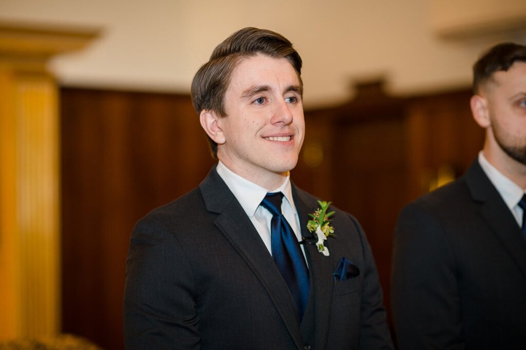 Groom watches smiling as his bride walks down the aisle at a church in stonington ct 