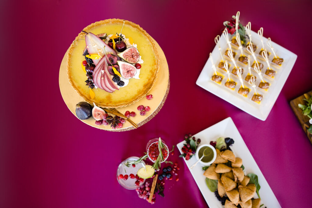 A variety of desserts and appetizers on a pink table.