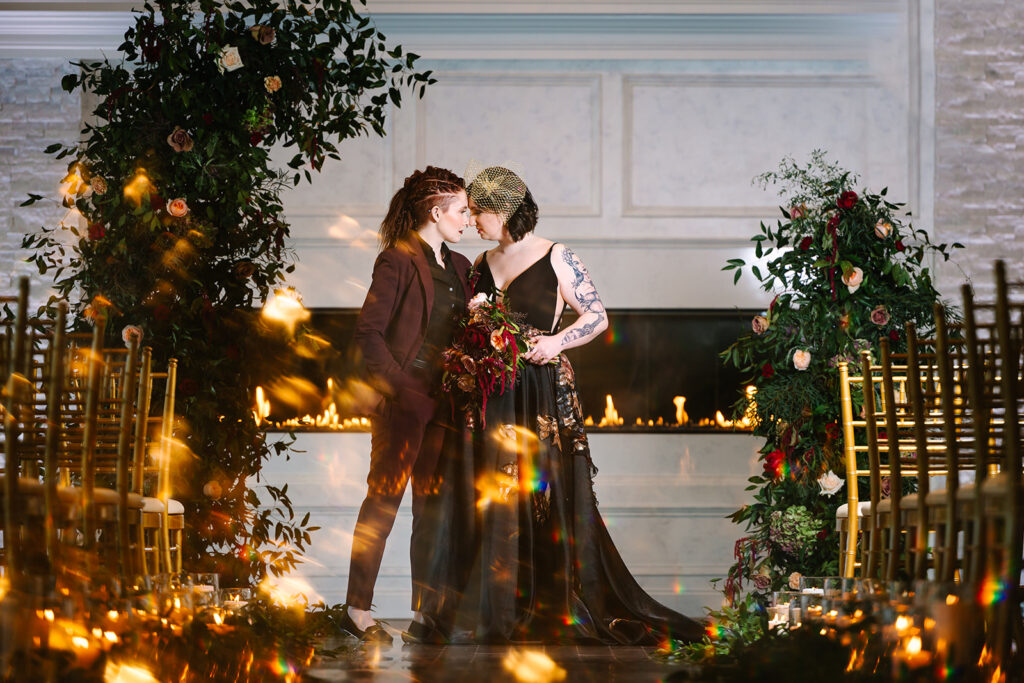 Two brides kissing in front of a fireplace.